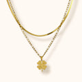 Close-up of layered gold chain necklace with clover pendant