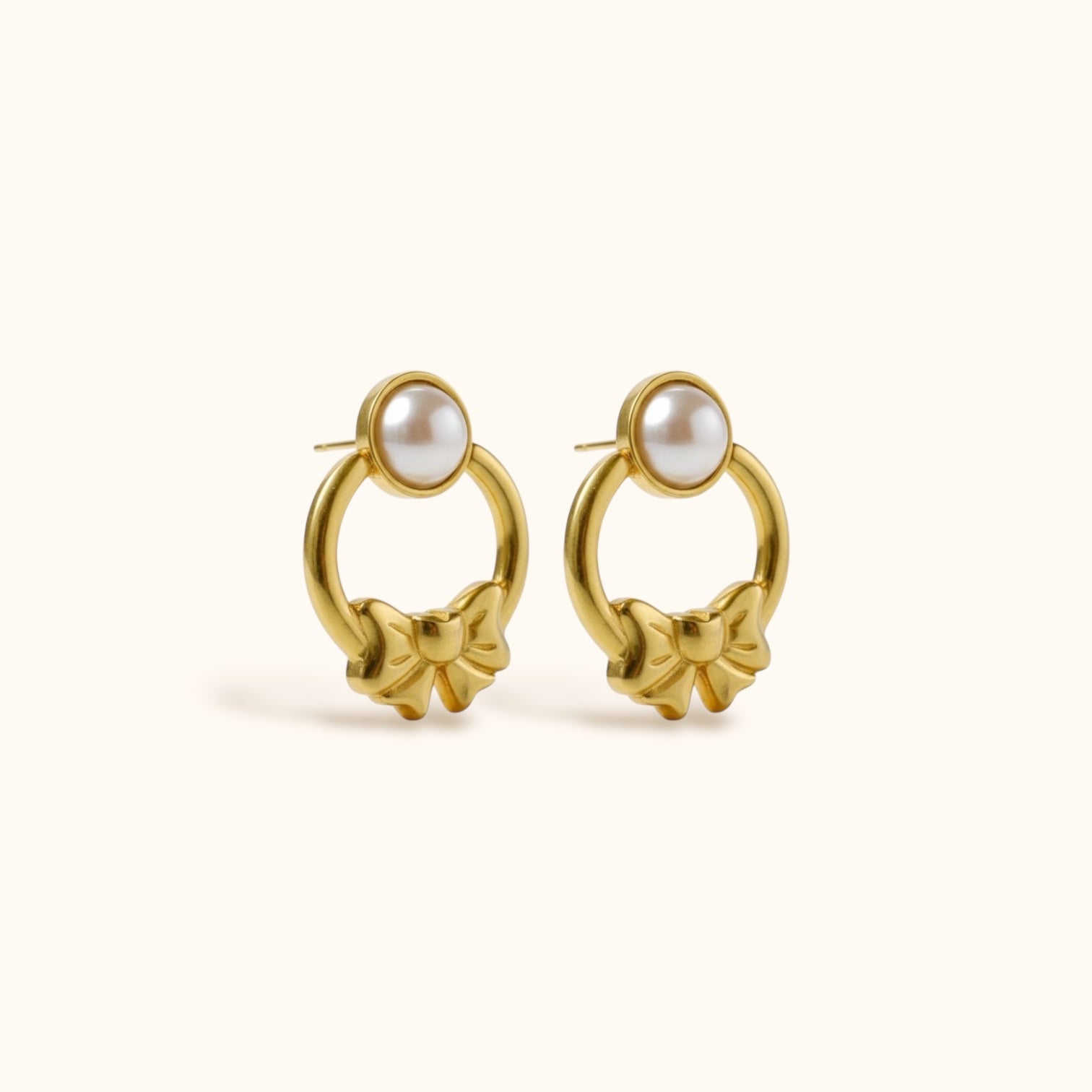 Gold-plated Lunelle Earrings with round circle, bow design, and pearl stud on neutral background