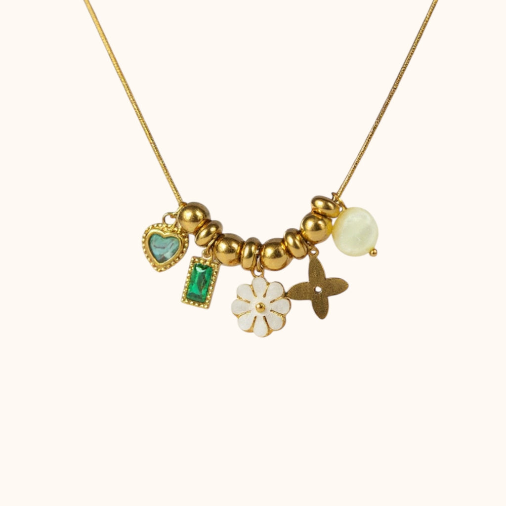 Gold-plated Petale Necklace with layered pendants: white flower, emerald square, and three playful charms on neutral background