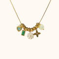Gold-plated Petale Necklace with layered pendants: white flower, emerald square, and three playful charms on neutral background