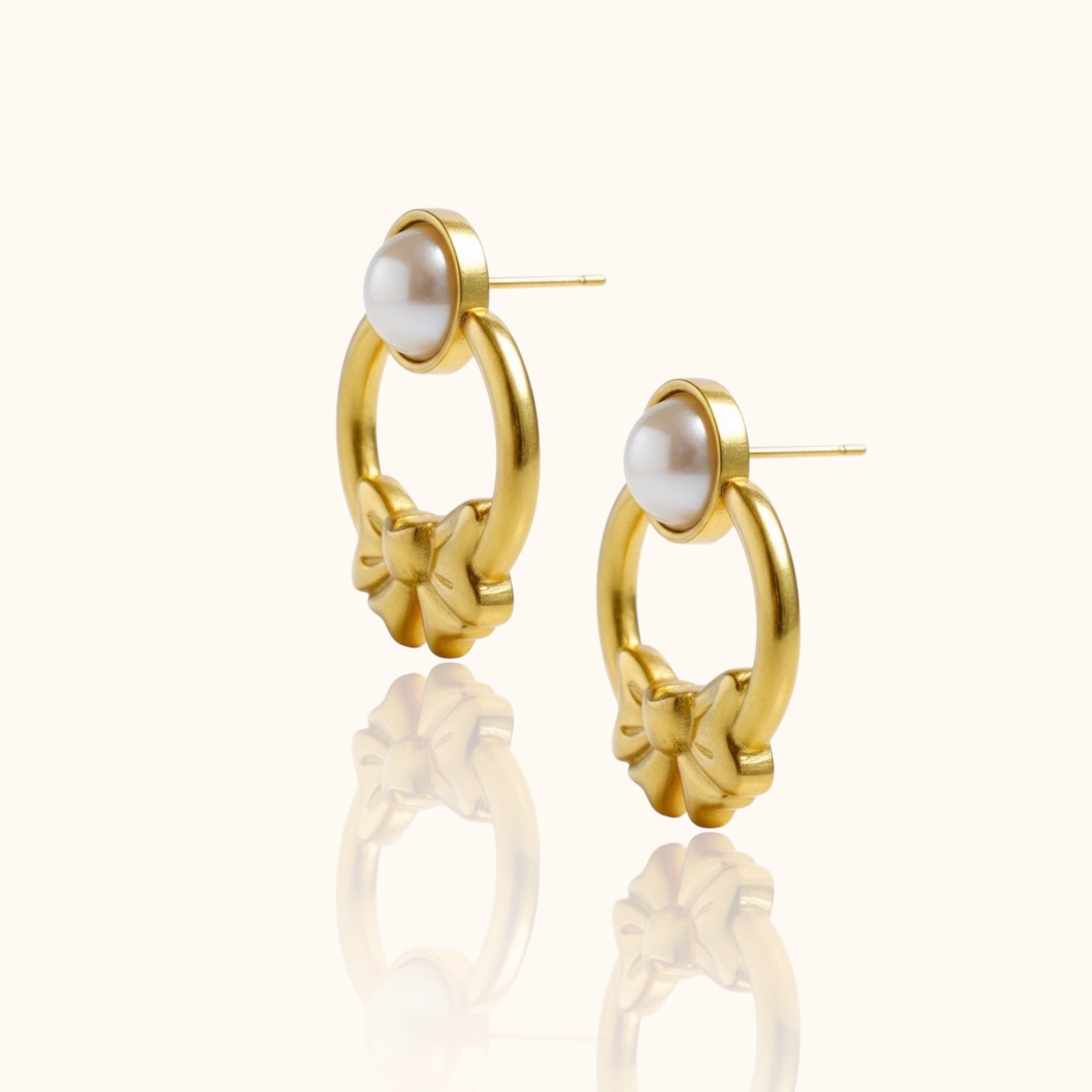Delicate gold bow earrings photographed on neutral-tone background for minimalist style